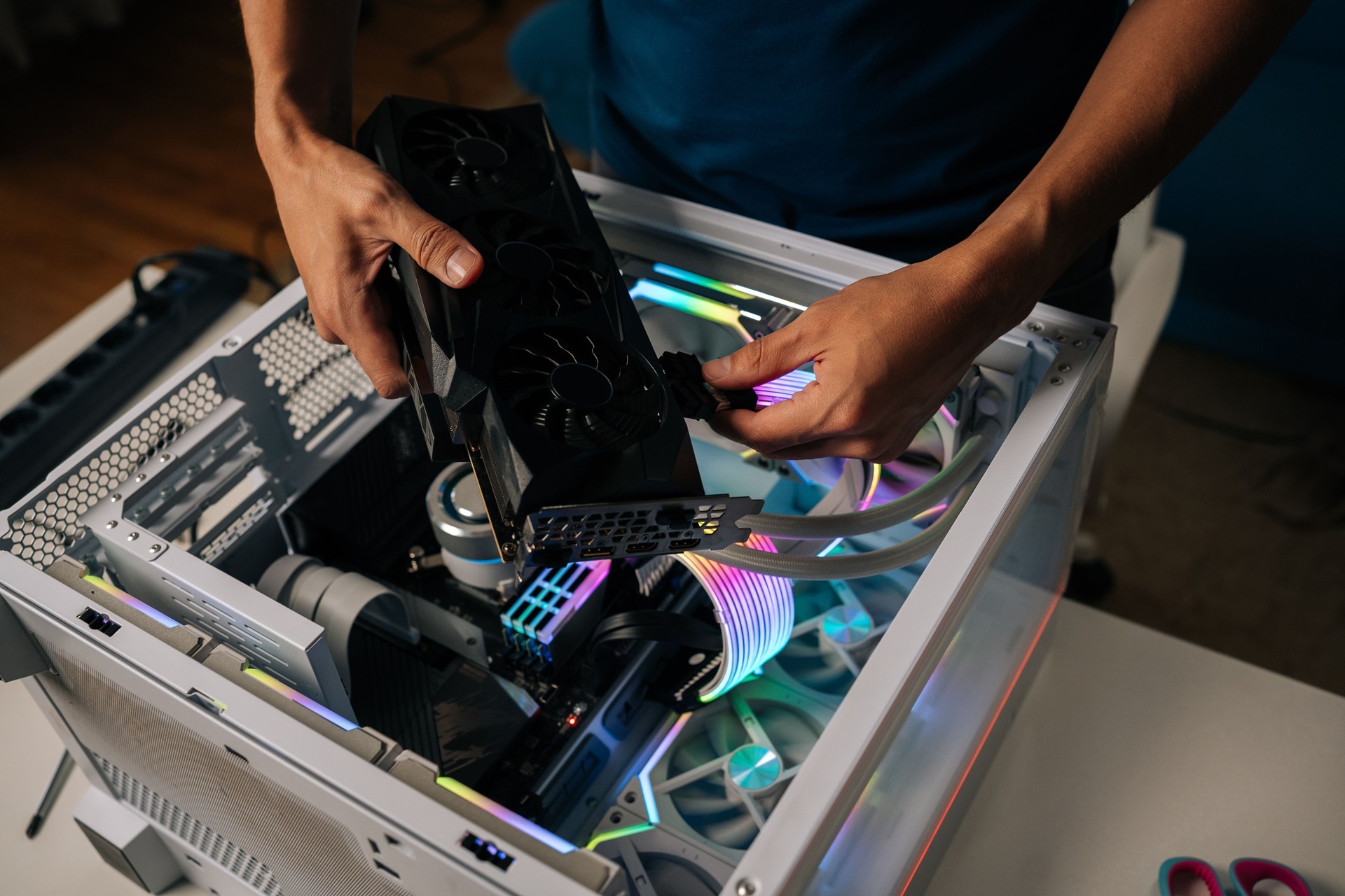 Skilled computer professional inserting high-performance graphics card into custom gaming pc, illuminating interior with vibrant RGB lighting